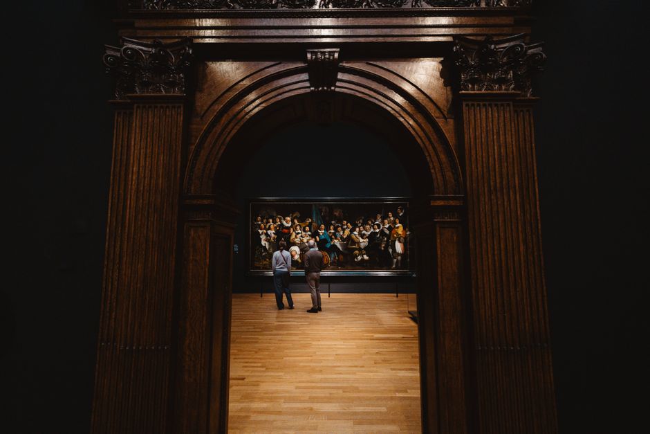 Two adults view a historic painting in Amsterdam museum's art exhibit.