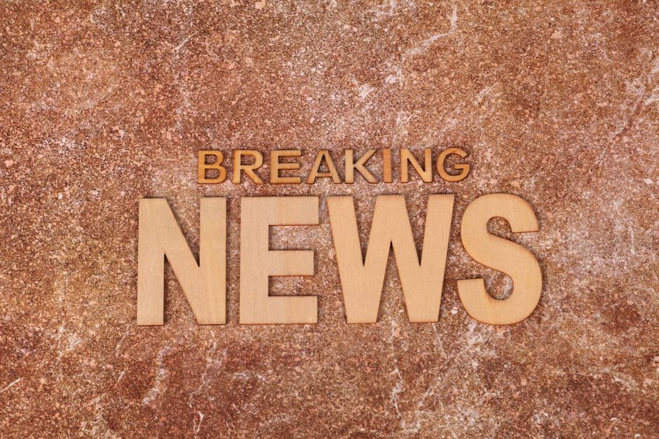 Wooden letters spell 'Breaking News' on a textured, marble-like background. Ideal for newsworthy content.